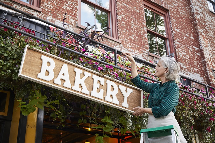 Older woman hanging a bakery sign